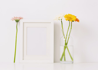 Empty frame mockup for design presentation and bouquet of flowers on a white wall background. Romantic minimalism design.