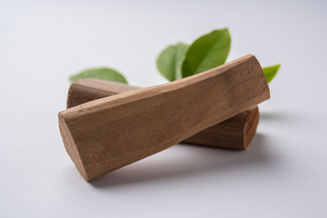 Chandan or sandalwood powder with traditional mortar, sandalwood sticks, perfume or oil and green...