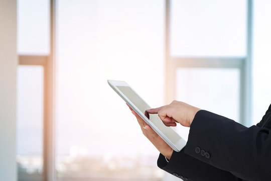 business woman use a pc tablet with blurred image of glass of office.