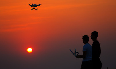 Fototapeta na wymiar Man operating of flying drone quadrocopter at sunset