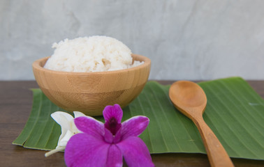 Cooked rice in bowl on green banana leaf spoon and orchid .