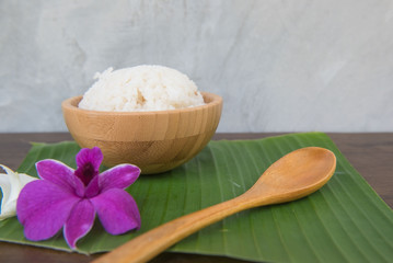Cooked rice in bowl on green banana leaf spoon and orchid .