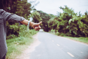 Young woman hitchhiking along a road.