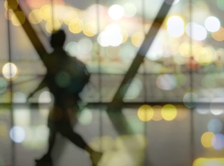 Blurred Silhouette of man with luggage walking at airport, showing something through the window.