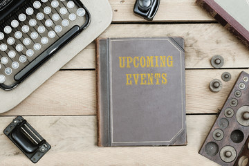 Upcoming Events on old book cover at office desk with vintage items