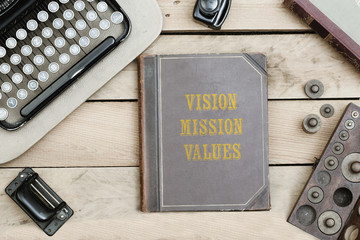Vision, Mission, Values on old book cover at office desk with vintage items © MichaelJBerlin