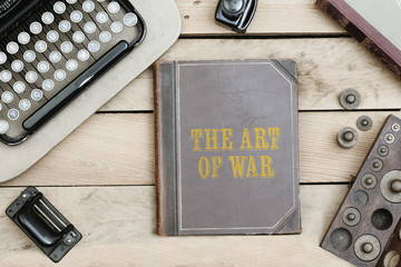 The Art of War on old book cover at office desk with vintage items © MichaelJBerlin