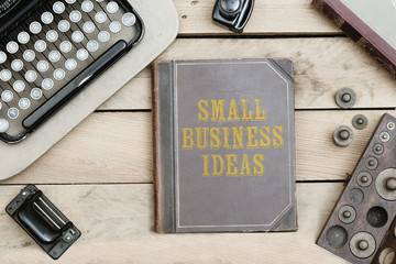 Small Business Ideas on old book cover at office desk with vintage items © MichaelJBerlin