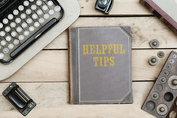 Helpful Tips on old book cover at office desk with vintage items © MichaelJBerlin