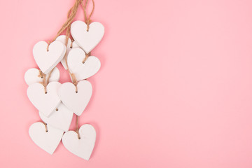 White wooden hearts on a pink background with space for text