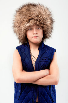 Portrait of cool young stylish boy in fur hat on light background