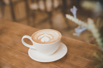 Vintage color tone of coffee latte art on wooden table in coffee shop.