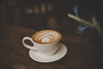 Vintage color tone of coffee latte art on wooden table in coffee shop.
