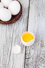 Broke One whole egg amongst white eggs in basket on a white background