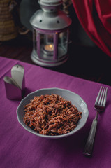 Dietary proper nutrition. A plate of brown rice on a beautiful purple table