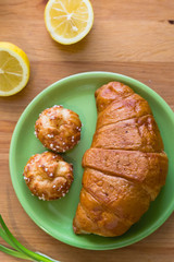 Tea with lemon and croissant for fresh spring breakfast on wooden table