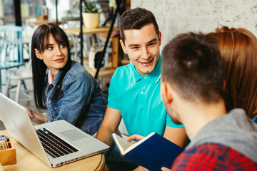 Group of students learning in a cafe with a laptop on the table in front of them