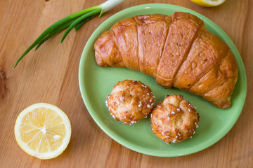 Tea with lemon and croissant for fresh spring breakfast on wooden table