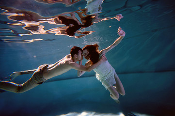 Underwater in the pool with the purest water. Loving couple hugging. The feeling of love closeness