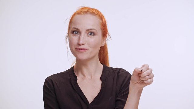 Middle-aged Caucasian female with colored orange hair eating imaginary fruit on white background in slowmotion