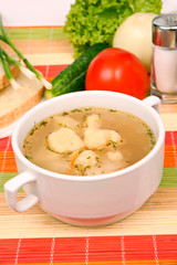 Ukrainian soup with dumplings in a white plate on a colored tablecloth