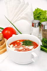 Puree soup with tomatoes in white plate with sour cream and parsley