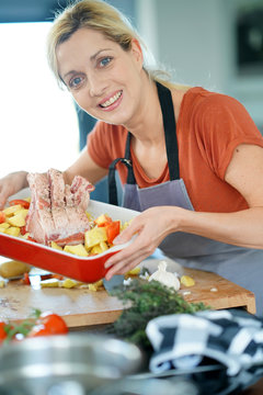 Portrait of smiling blond woman in kitchen cooking for dinner