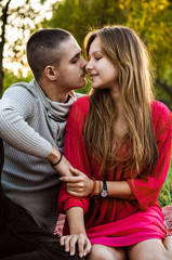 Fototapeta premium Happy young couple sitting in the park and hold hands in love