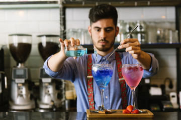 Barman is making cocktail at night club.