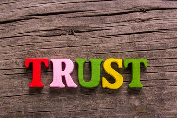 trust word made from colored wooden letters on an old table. Concept