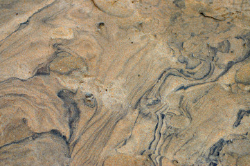 Volcanic sand pattern with black streaks running through it.