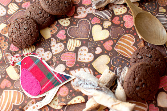Red toy bird and cookies on dark napkin with image of hearts