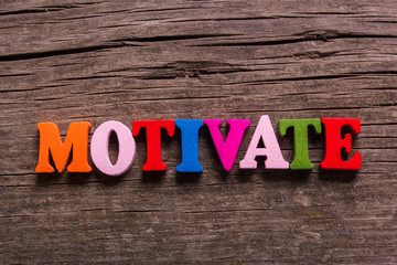 Naklejka premium motivate word made from colored wooden letters on an old table. Concept