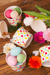 Easter flower arrangement and colorful eggs on a wooden surface