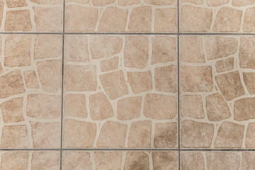 Ceramic beige or light brown tiles. Texture of floor covering in the office, store, shopping center, business center.