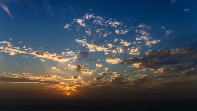 4k time lapse of clouds crossing the amazing sky over the sea or ocean at sunset. transition from day to night. The clouds cross slowly from left to right colored yellow orange purple blue.
