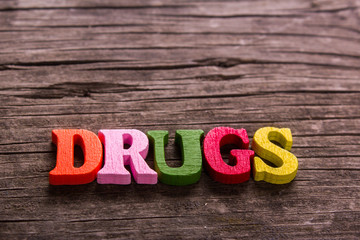 drugs word made from colored wooden letters on an old table. Concept