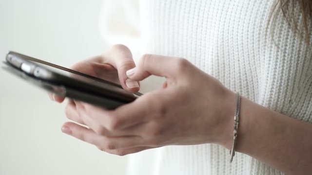 Closeup shot of female hands holding smartphone, typing text on touch screen