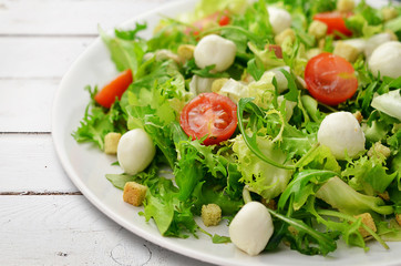 Fresh salad on white plate on wooden planks