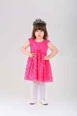 beautiful little girl in pink Princess dress with crown on gray 