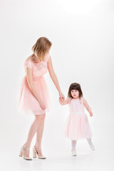 blonde mom holding the hand of sweet little daughter in pink dre