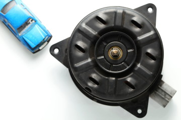 The used and damaged old fan motor unit with model toy car put beside represent the car part and maintenance concept related idea.