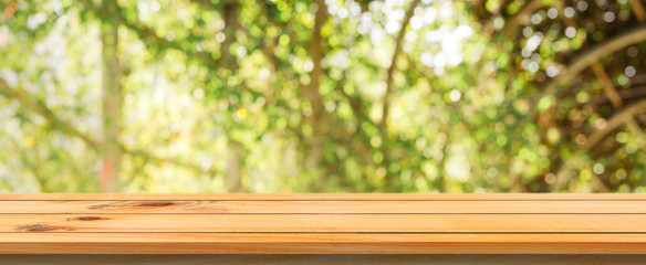 Wooden board empty table blurred background. Perspective brown wood table over blur trees forest background - can be used mock up for display or montage your products. spring season. panoramic banner.