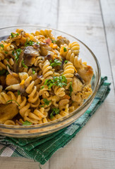 Integral pasta with chicken, mushrooms, vegetables, spices. White wooden background.