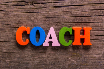 coach word made from colored wooden letters on an old table. Concept