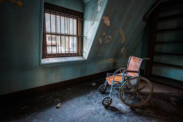 Fototapeta na wymiar Old wheel chair near a window 