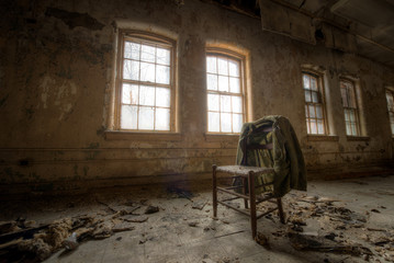 Old suit coat hanging on a chair in an abandoned room