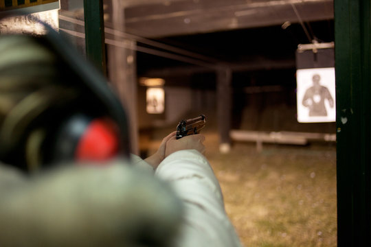 woman shooting with gun at target in shooting range