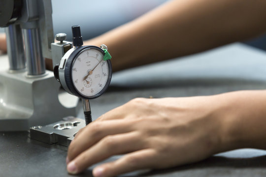 worker measure part precision by dial guage