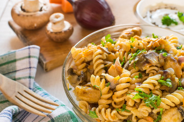 Integral pasta with chicken, mushrooms, vegetables, spices and Greek yogurt. White wooden background.